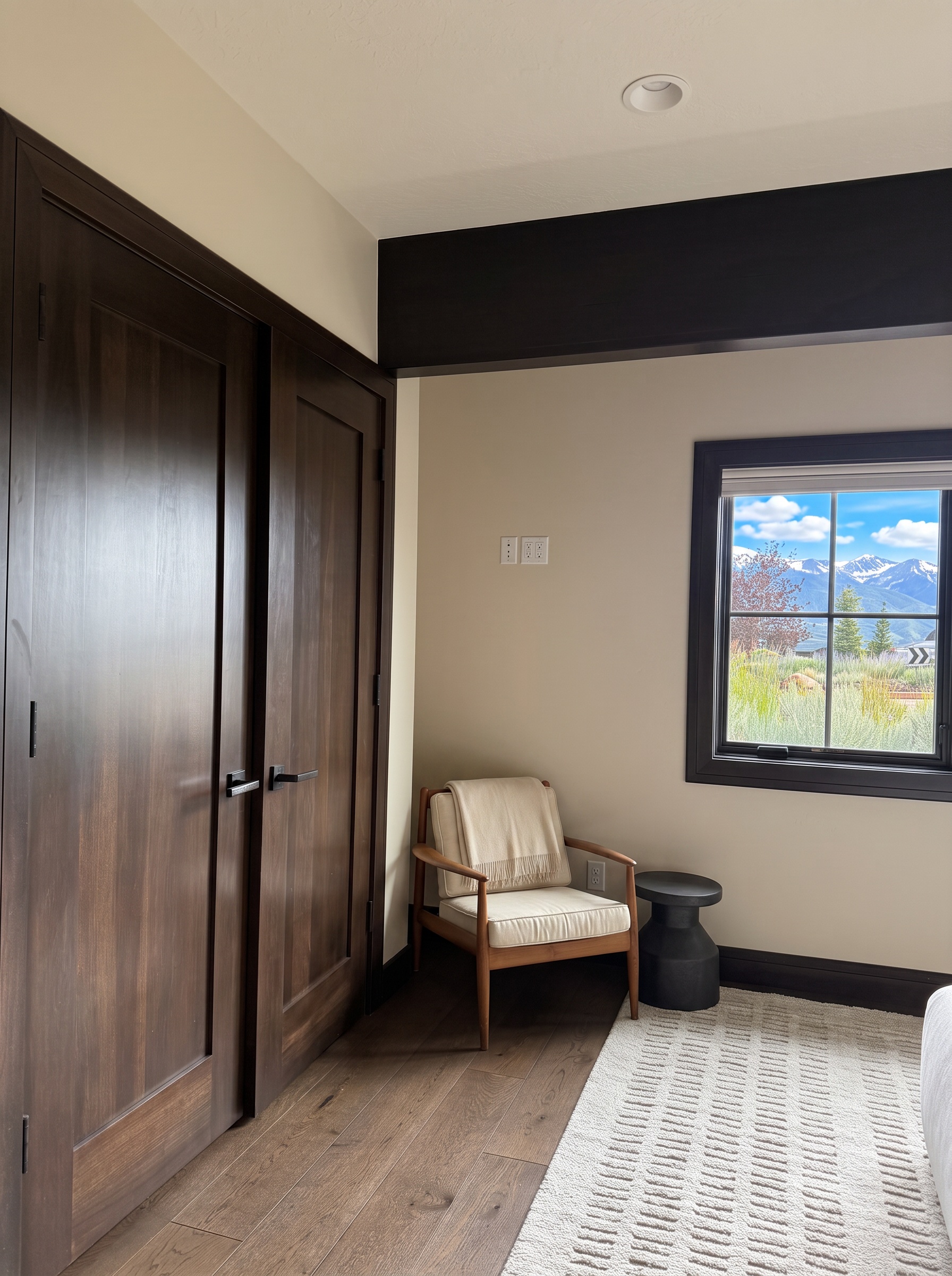 Reading corner with a wood chair and a window overlooking the mountains and meadow