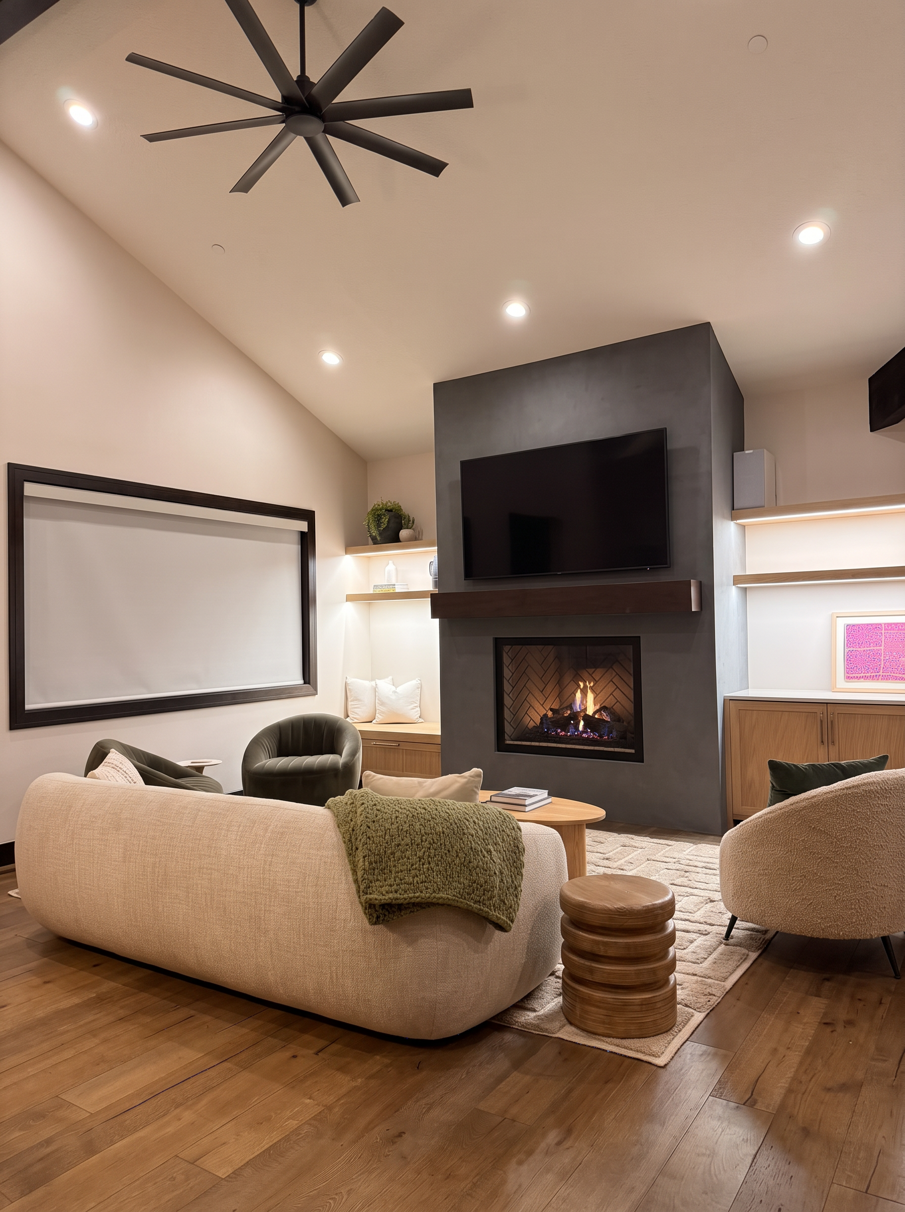 Great room at dusk with the herringbone fireplace lit and backlit oak shelving