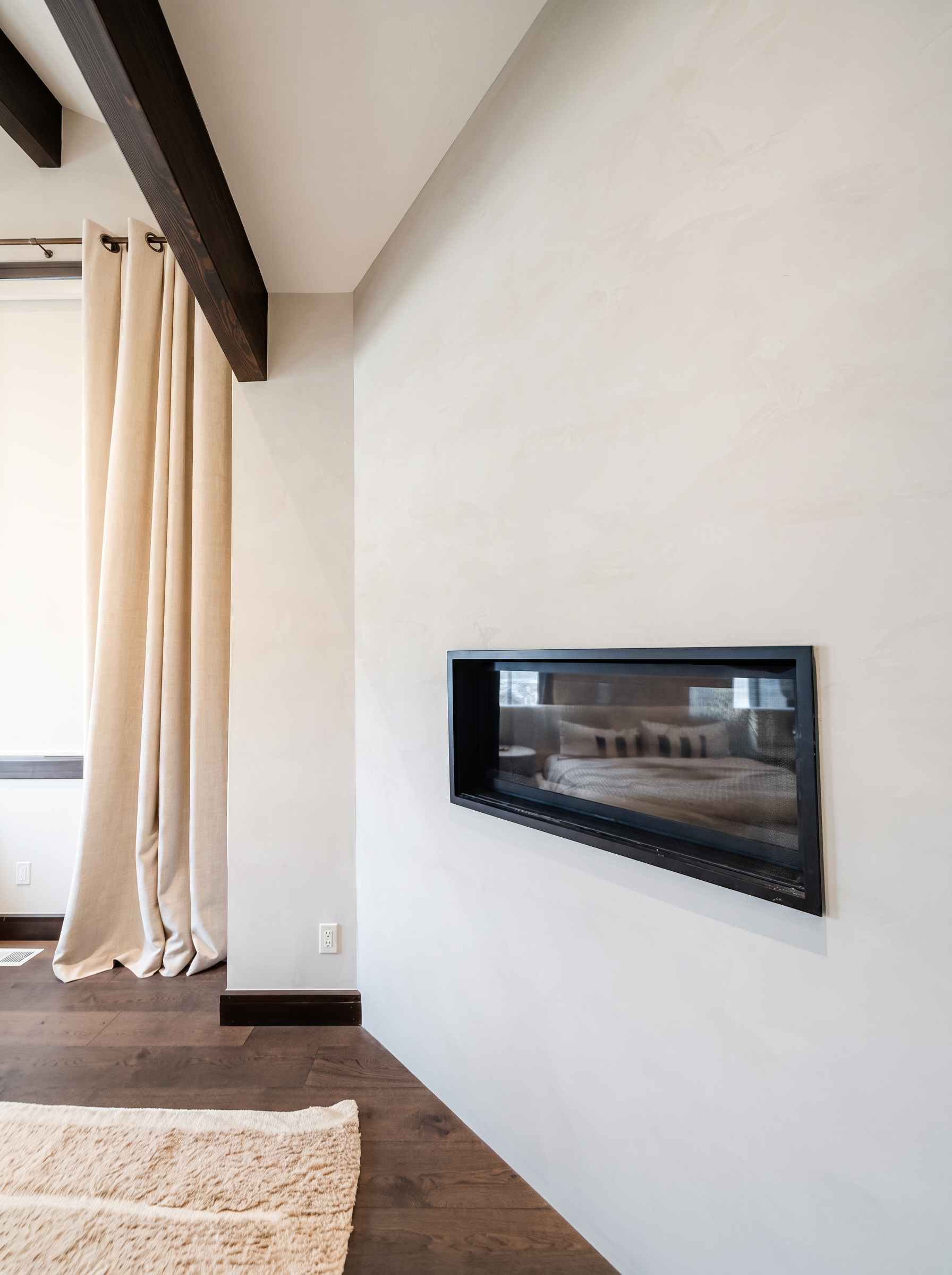 See-through fireplace in the primary suite with exposed beams and linen curtains