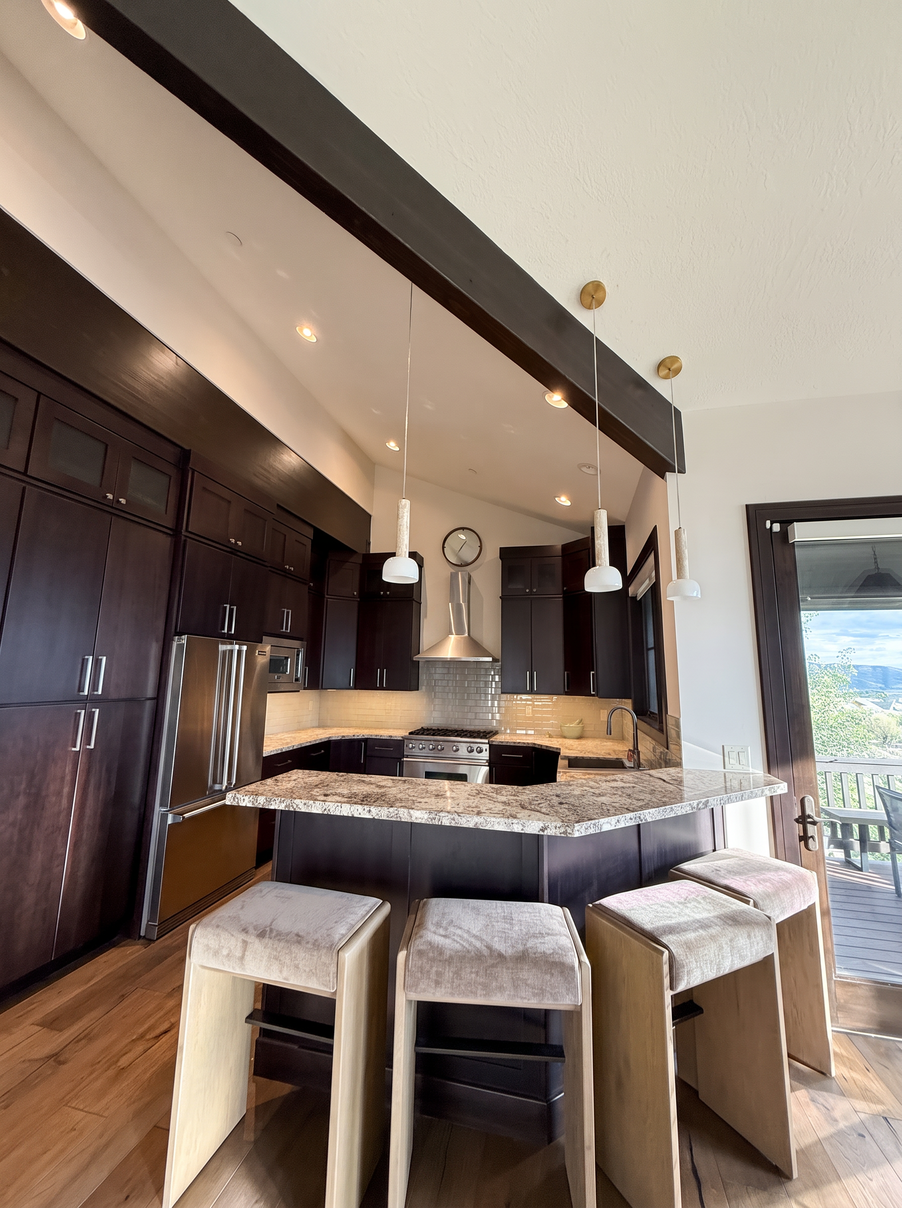 Kitchen island with granite countertops, espresso cabinets, and bar stools