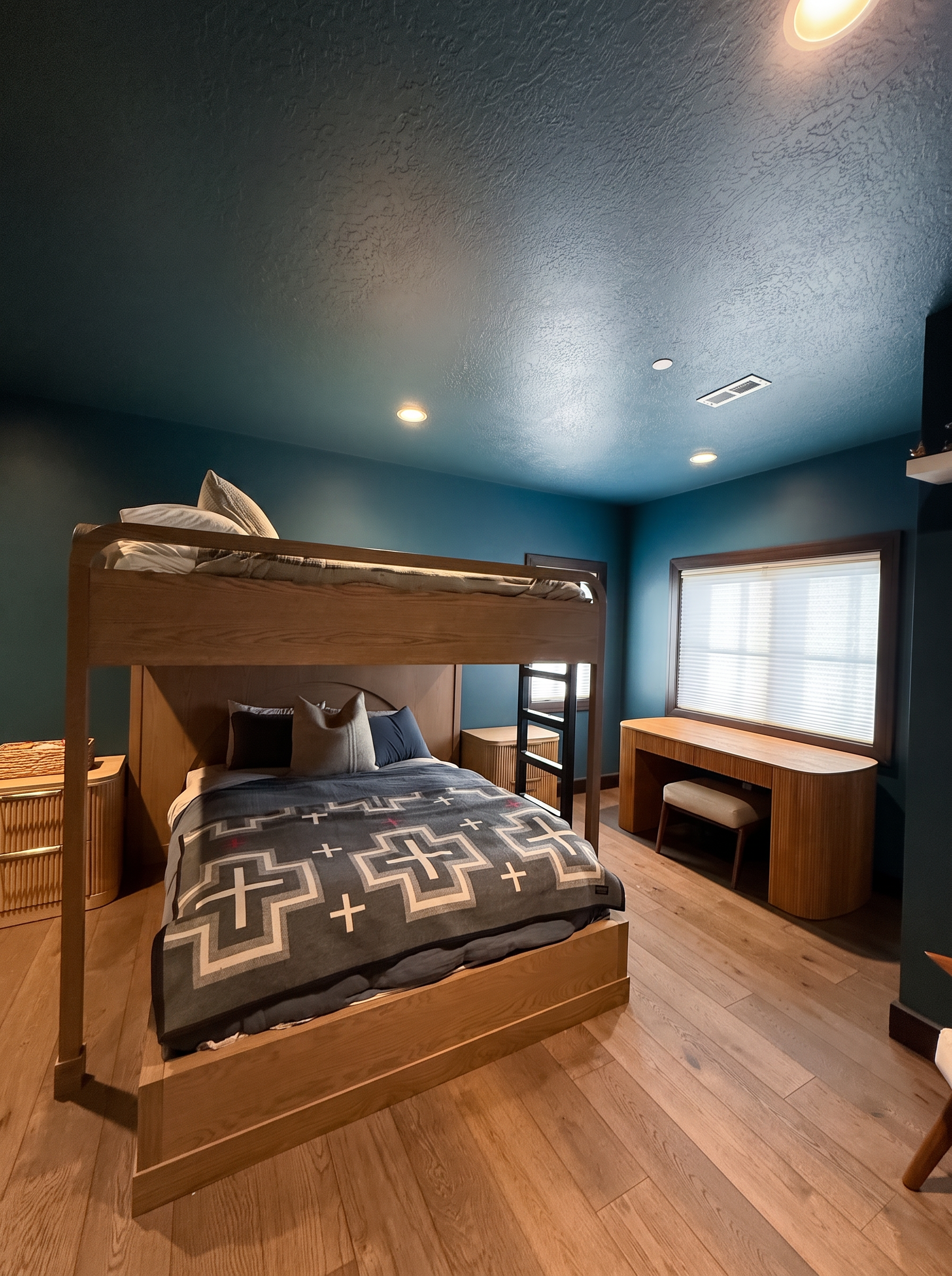Bunk room with a custom oak bunk over a queen bed, deep teal walls, and a built-in desk
