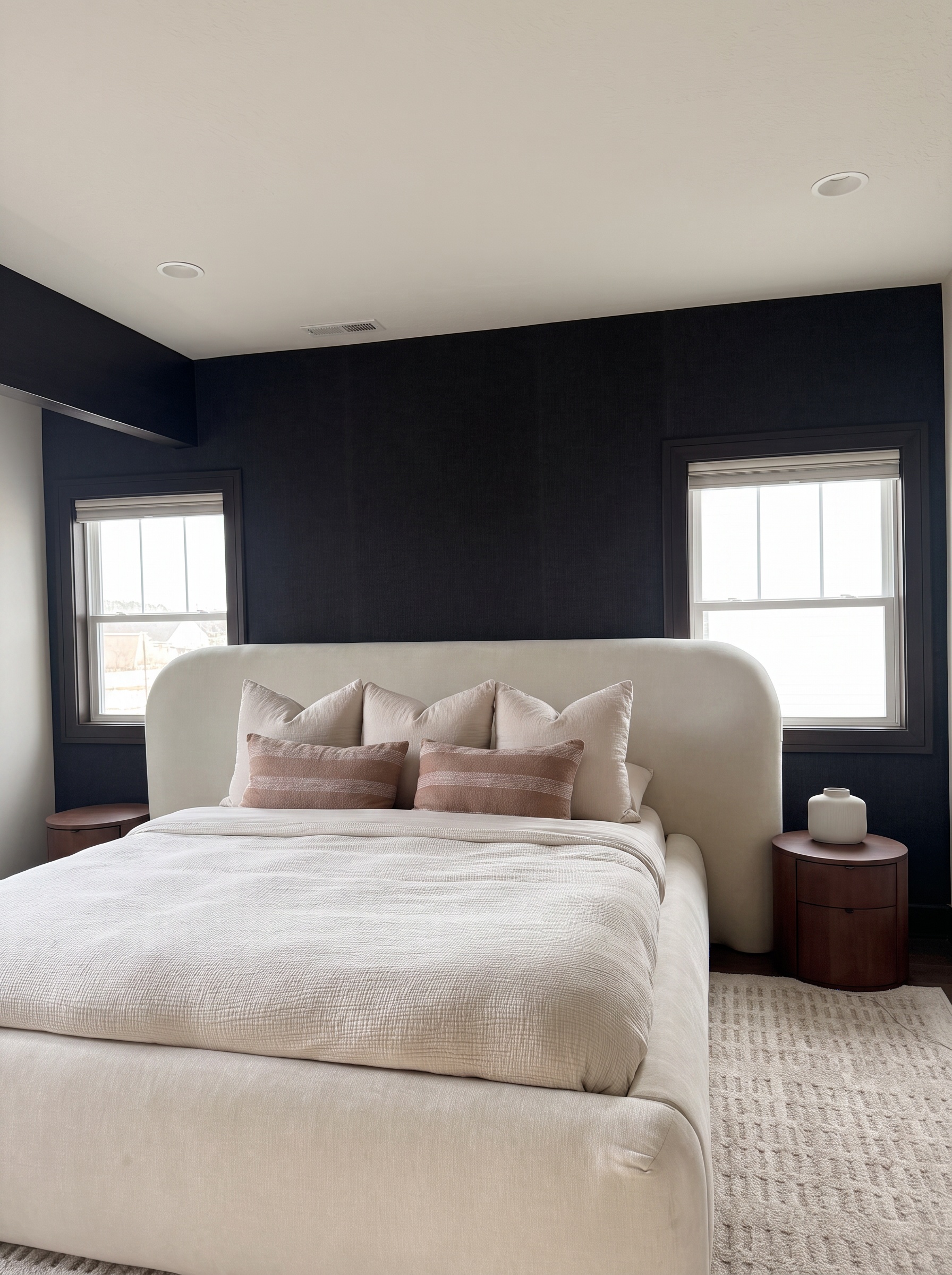 Detail of the king bed's upholstered headboard and layered neutral linens