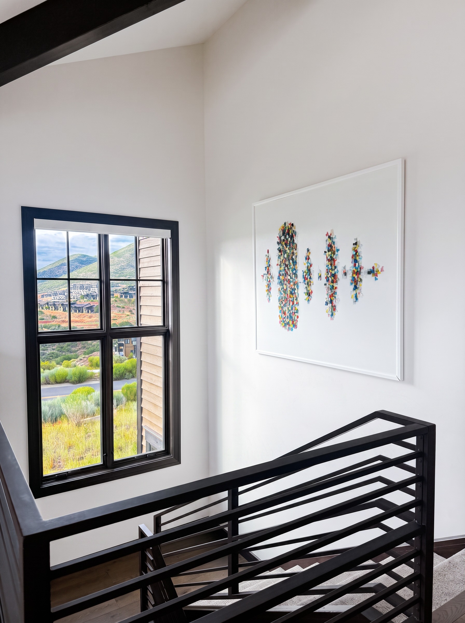 Black staircase and large colorful artwork with a mountain view window