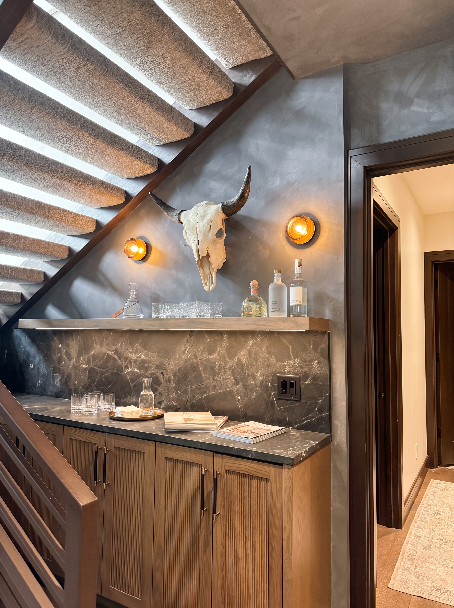 Moody lower level bar under the staircase with oak cabinetry, a beverage fridge, and dark marble