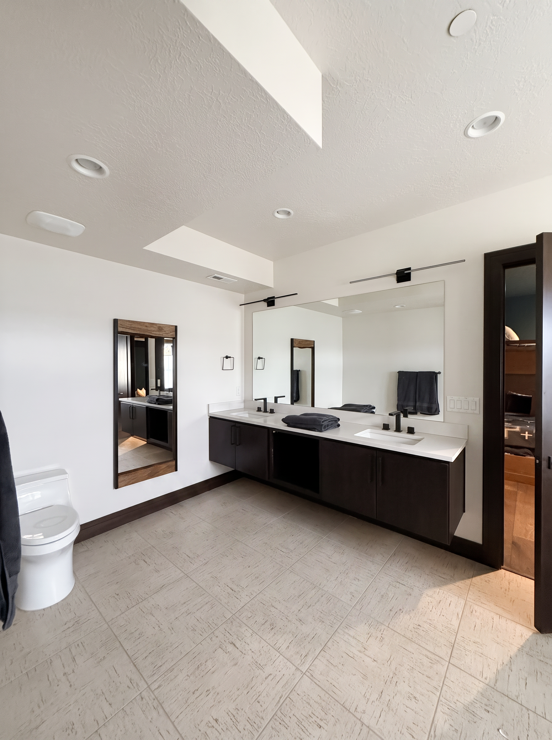 Oversized bunk room bath with a long double vanity, espresso cabinets, and large mirrors