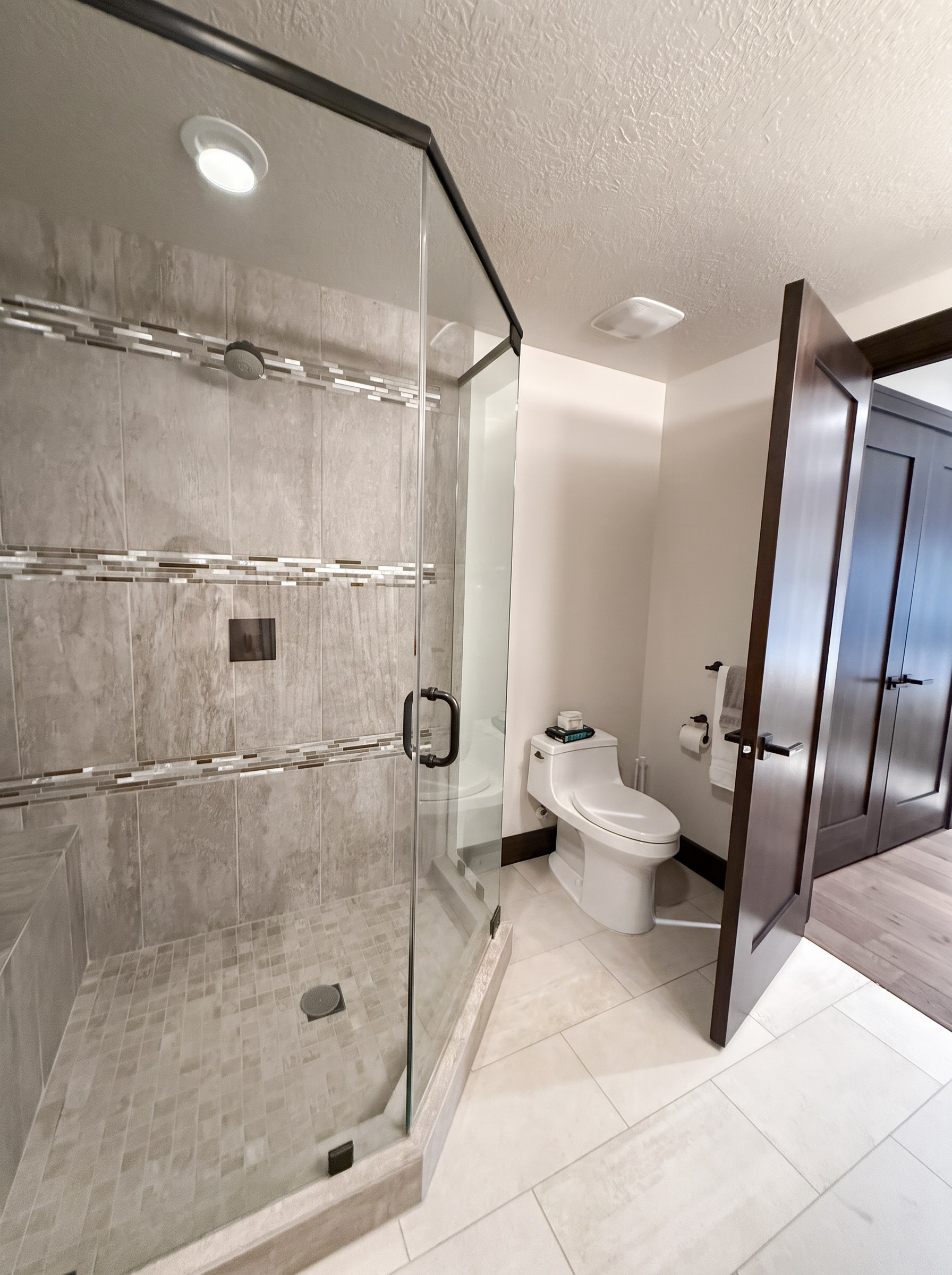 Frameless glass corner shower with stone tile and glass mosaic inlay bands